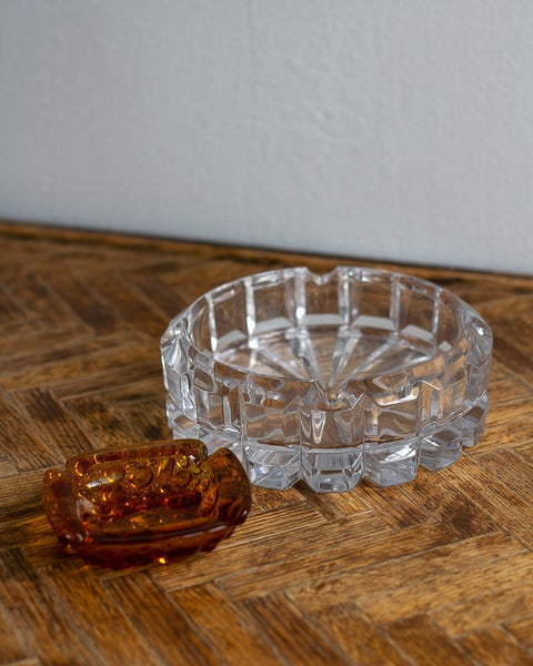 Vintage clear glass ashtray and amber glass dish on a vintage chevron-patterned wooden side-table with a neutral white background wall. All items curated by Parliament Interiors in Vancouver, BC.
