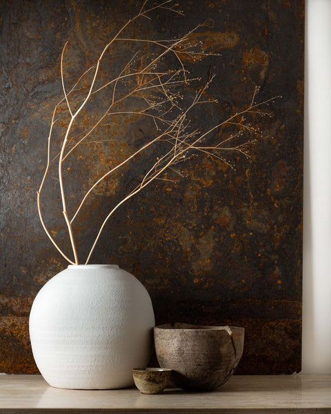 Vintage white ceramic vase with dried branches against a textured dark wall. A vintage medium wood bowl and vintage small brown and beige ceramic bowl are beside the vase. All items are curated by Parliament Interiors in Vancouver, BC.